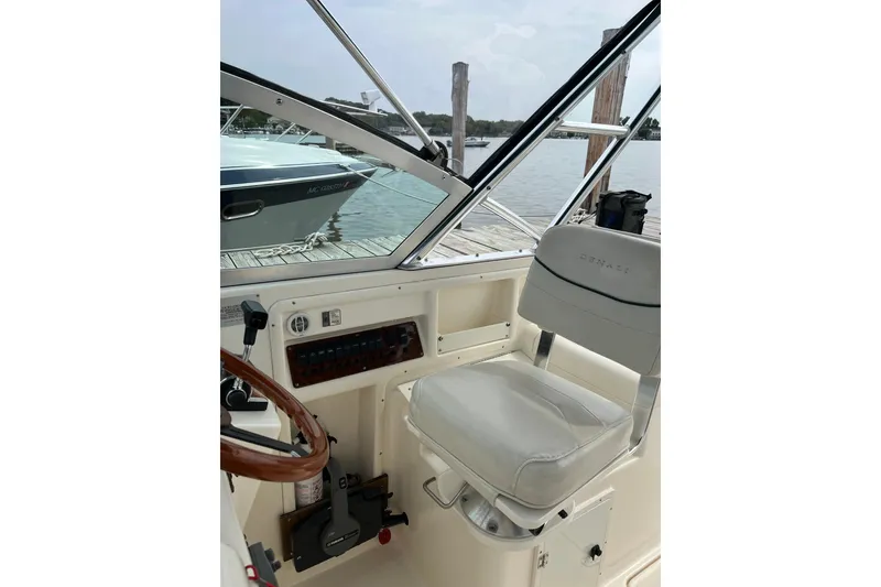 Slide: The Image of Helm of 2000 Pursuit 2860 Denali boat with white captain's chair and wooden steering wheel. - 13