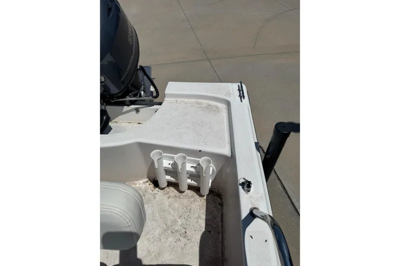 Slide: The Image of 2018 Edgewater 158CS boat deck with rod holders and motor, parked on concrete. - 10