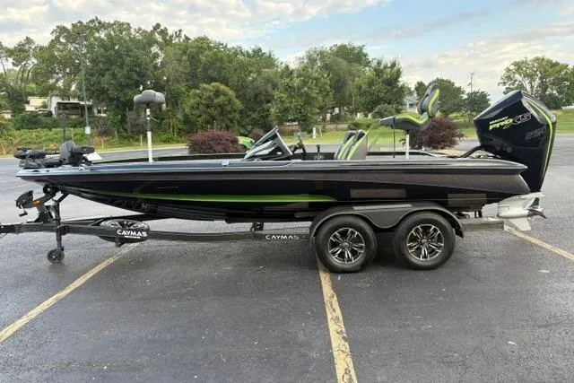 Slide: The Image of 2023 Caymas CX 20 PRO bass boat on trailer, black with green accents, parked outdoors. - 3