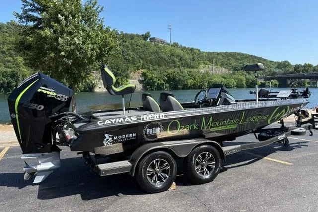 Slide: The Image of 2023 Caymas CX 20 PRO boat with custom graphics, parked near a scenic river. - 6