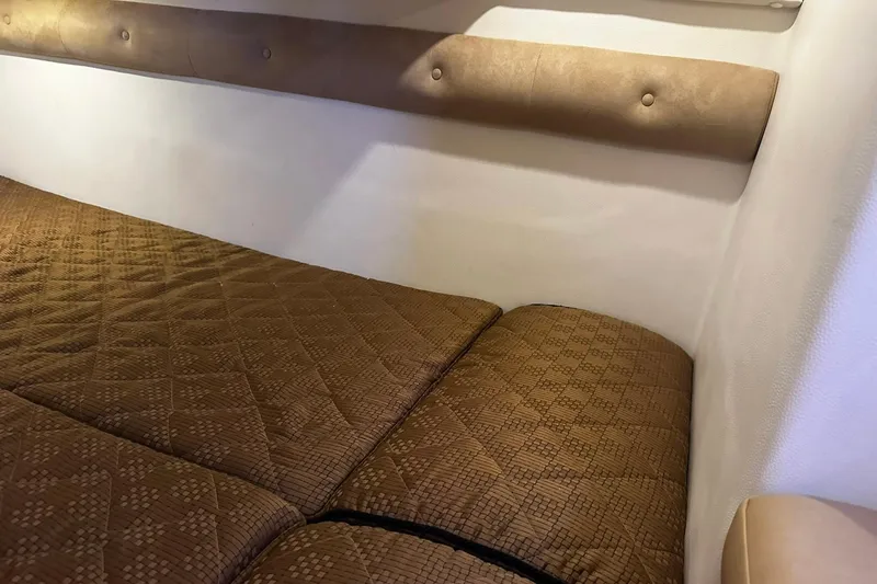 Slide: The Image of Interior cabin of 2012 Rinker 310 Express Cruiser LE with brown quilted bedding. - 34