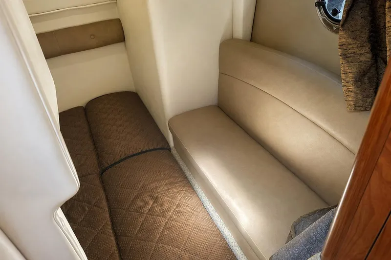Slide: The Image of Interior cabin of 2012 Rinker 310 Express Cruiser LE with beige seating and brown bedding. - 33