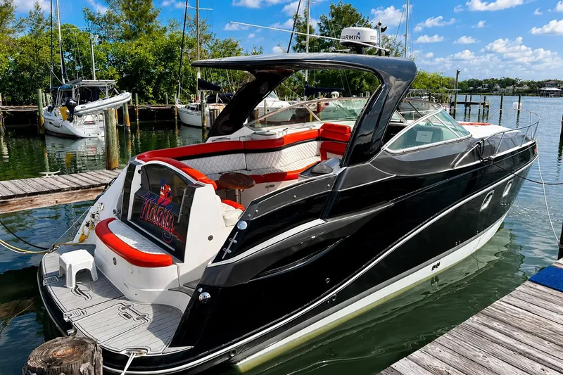 Slide: The Image of 2012 Rinker 310 Express Cruiser LE docked, featuring sleek black design and spacious seating. - 9