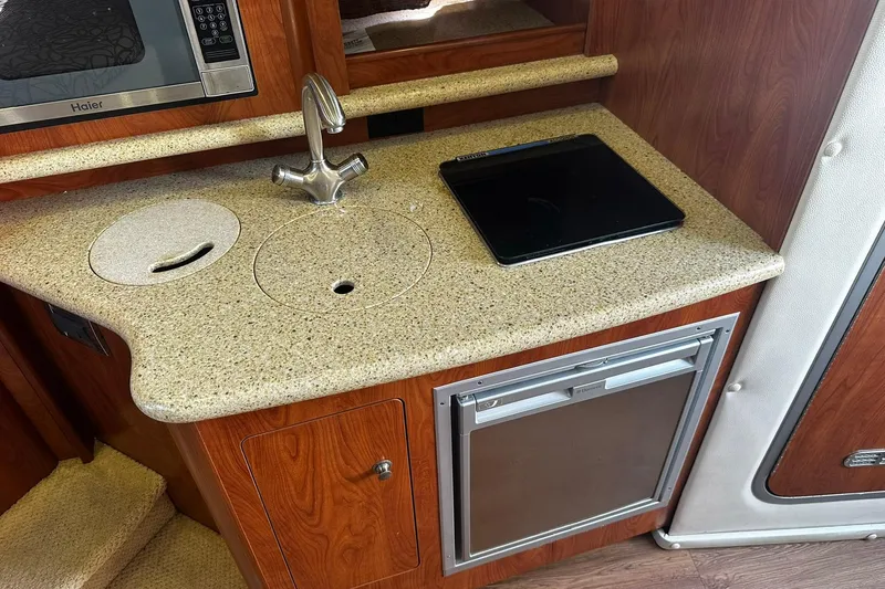 Slide: The Image of 2012 Rinker 310 Express Cruiser LE kitchenette with sink, microwave, and mini-fridge. - 47