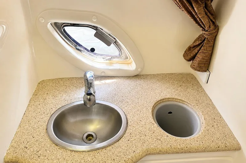 Slide: The Image of 2012 Rinker 310 Express Cruiser LE bathroom sink with porthole and countertop. - 53