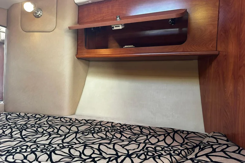 Slide: The Image of Interior cabin of 2012 Rinker 310 Express Cruiser LE with patterned bedding and wooden storage. - 42