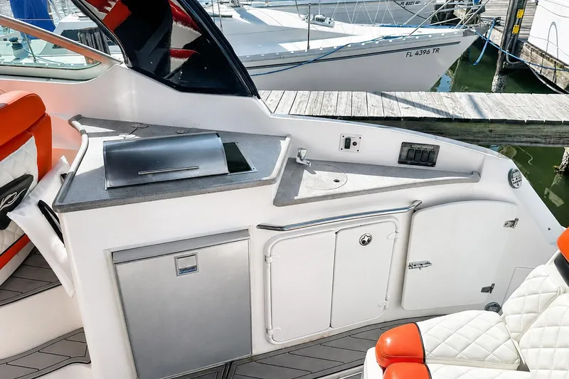Slide: The Image of 2012 Rinker 310 Express Cruiser LE cockpit with kitchenette and seating area. - 14