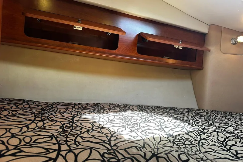 Slide: The Image of 2012 Rinker 310 Express Cruiser LE cabin with patterned bedding and wooden storage compartments. - 41