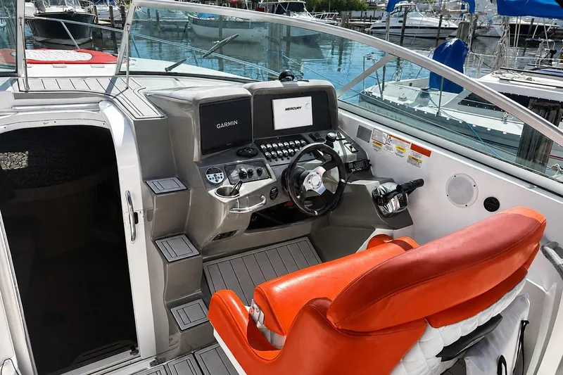 Slide: The Image of 2012 Rinker 310 Express Cruiser LE helm with Garmin navigation and vibrant orange seating. - 24