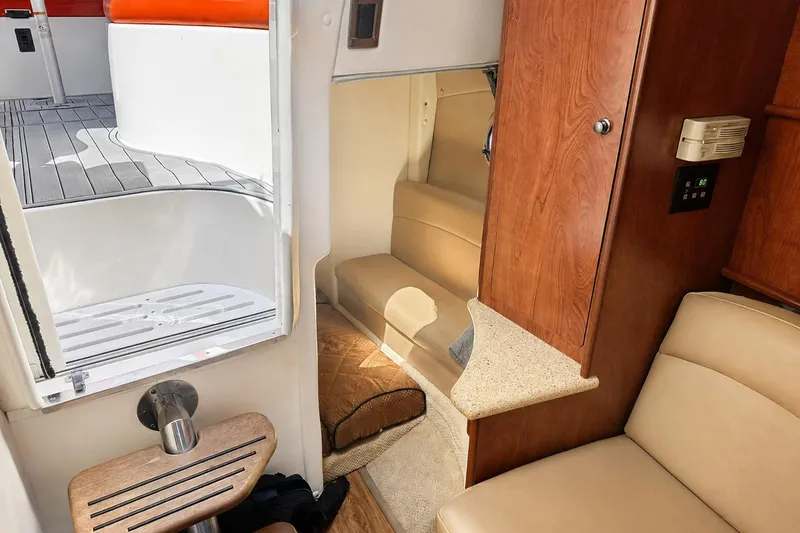 Slide: The Image of Interior of 2012 Rinker 310 Express Cruiser LE, featuring cozy seating and wooden cabinetry. - 32