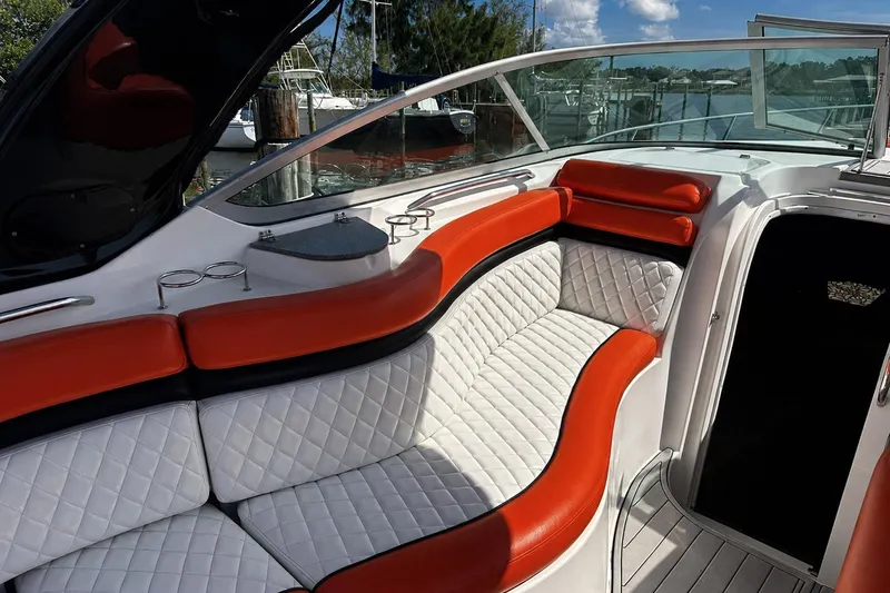 Slide: The Image of 2012 Rinker 310 Express Cruiser LE interior with red and white seating, docked by water. - 22