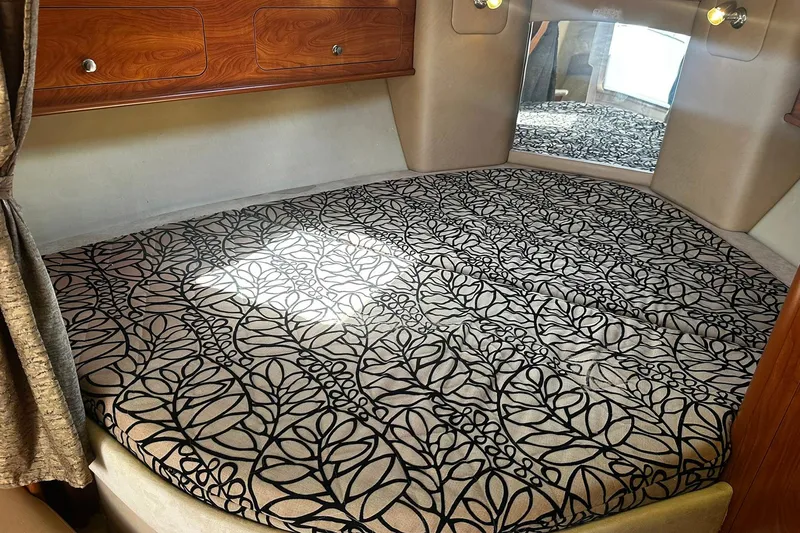 Slide: The Image of Interior cabin of 2012 Rinker 310 Express Cruiser LE with patterned bedding and wood accents. - 39