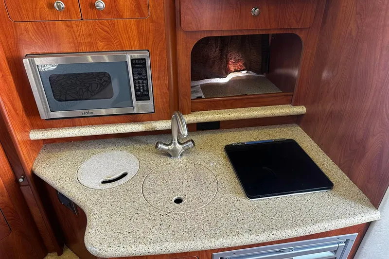 Slide: The Image of 2012 Rinker 310 Express Cruiser LE kitchen with microwave, sink, and cooktop. - 45