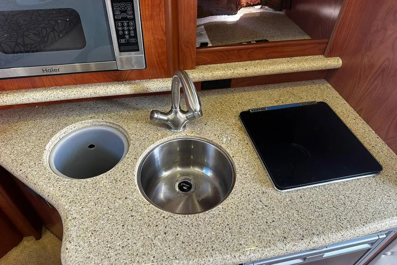 Slide: The Image of 2012 Rinker 310 Express Cruiser LE kitchen with sink, microwave, and cooktop. - 46