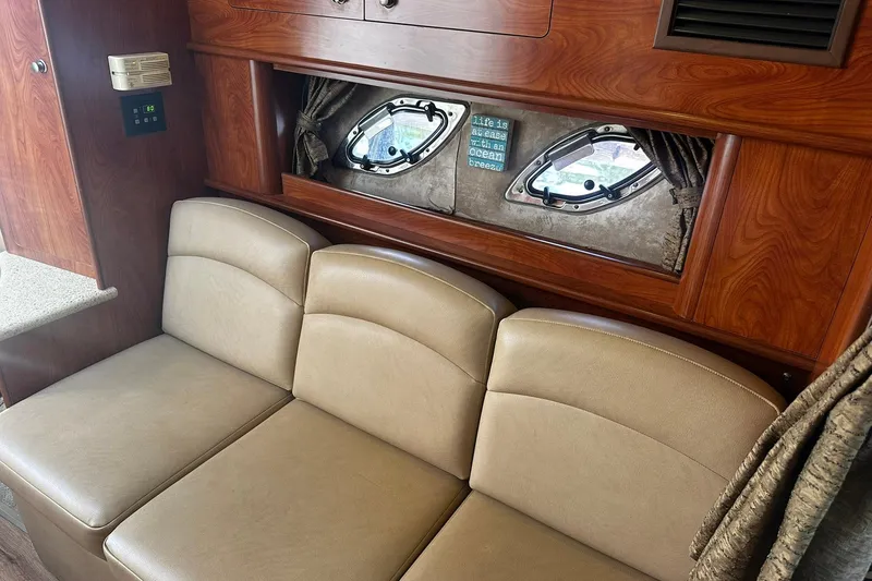 Slide: The Image of Interior of 2012 Rinker 310 Express Cruiser LE with beige seating and wood accents. - 36