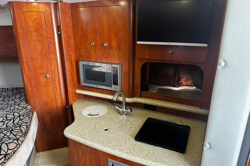 Slide: The Image of 2012 Rinker 310 Express Cruiser LE interior with kitchenette, microwave, and TV. - 48