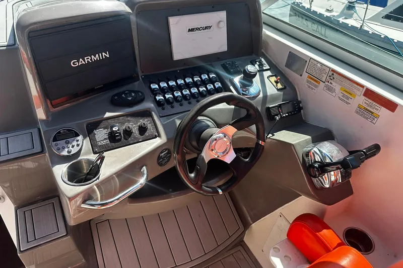 Slide: The Image of 2012 Rinker 310 Express Cruiser LE helm with Garmin and Mercury controls. - 25