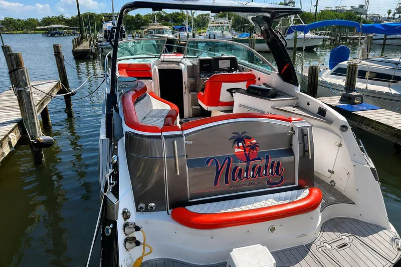 Slide: The Image of 2012 Rinker 310 Express Cruiser LE docked, featuring red and white seating, with "Nataly" branding. - 6