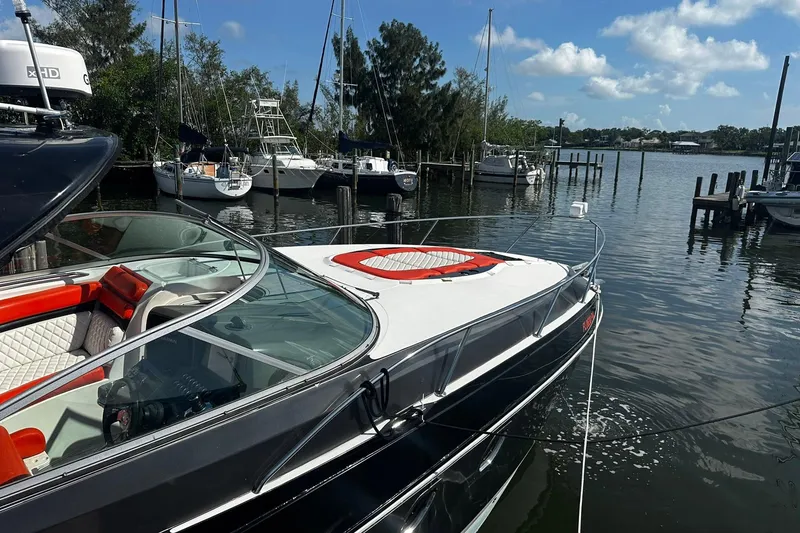 Slide: The Image of 2012 Rinker 310 Express Cruiser LE docked at a marina, surrounded by sailboats. - 10