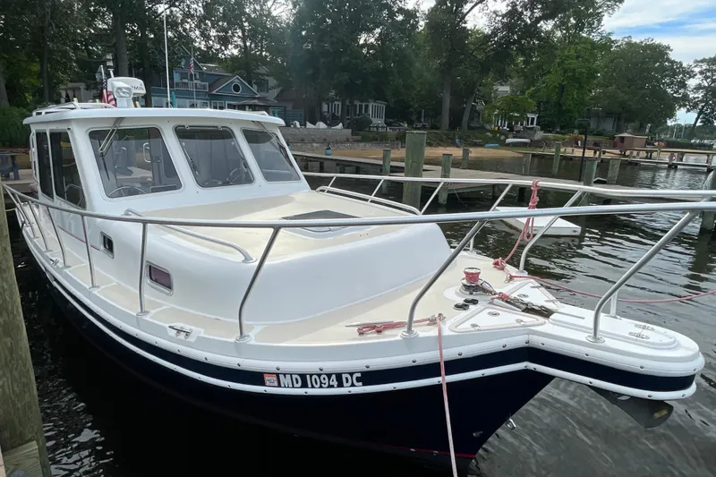 Slide: The Image of 2005 Fox Island Thirty Sedan Cruiser docked by a scenic waterfront. - 3