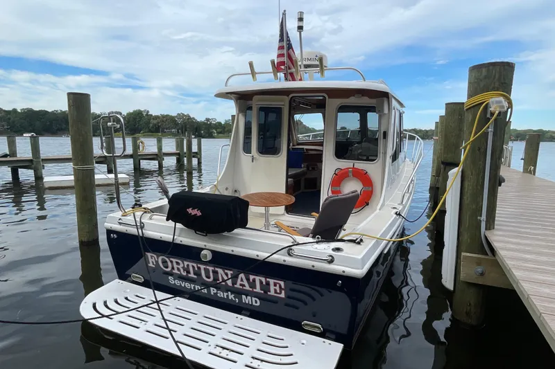 Slide: The Image of Fox Island Thirty Sedan Cruiser 2005 docked, featuring a spacious deck and serene waterfront view. - 1