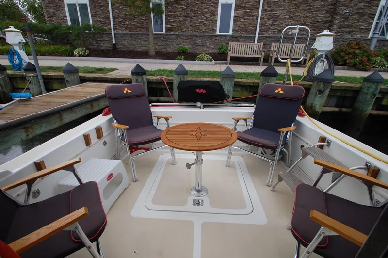 Slide: The Image of The image shows the aft deck of a 2005 Fox Island Thirty - Sedan Cruiser with four chairs around a round table. - 7