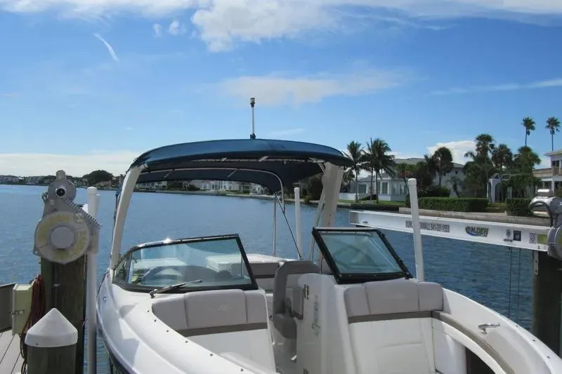 Slide: The Image of 2011 Sea Ray SLX 250 boat docked by a scenic waterfront under a clear blue sky. - 13