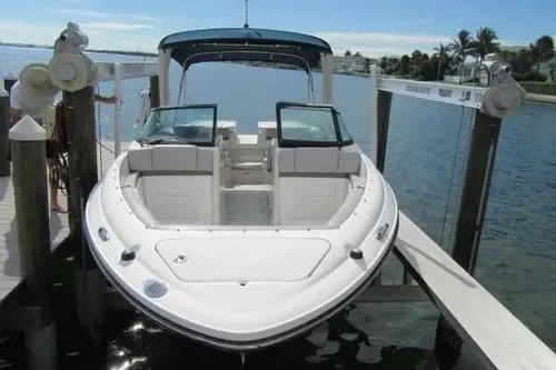 Slide: The Image of 2011 Sea Ray SLX 250 boat docked by the water, featuring sleek design and spacious seating. - 2