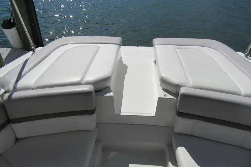 Slide: The Image of 2011 Sea Ray SLX 250 boat interior with white cushioned seating by the water. - 35