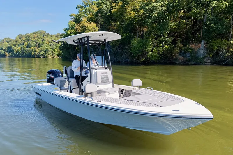 Slide: The Image of 2027 Pathfinder 2200 Hybrid boat cruising on a scenic lake with lush green trees. - 5
