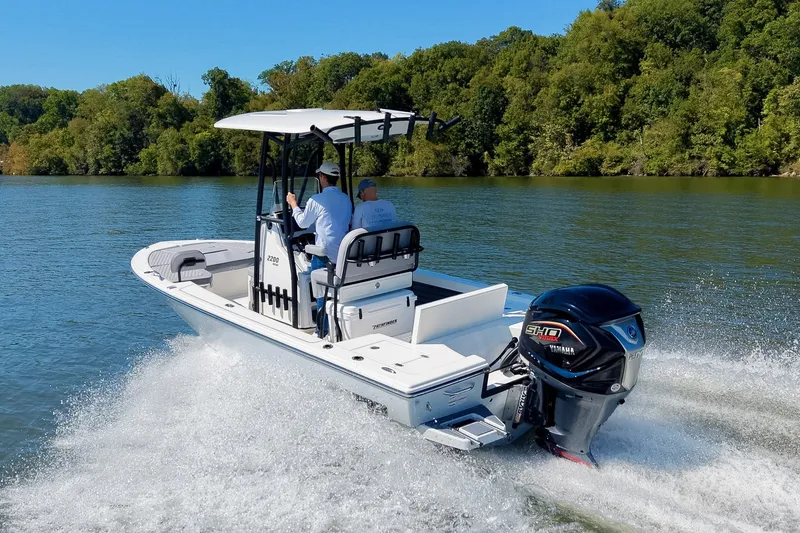 Slide: The Image of 2027 Pathfinder 2200 Hybrid boat cruising on a scenic river with lush green trees. - 3