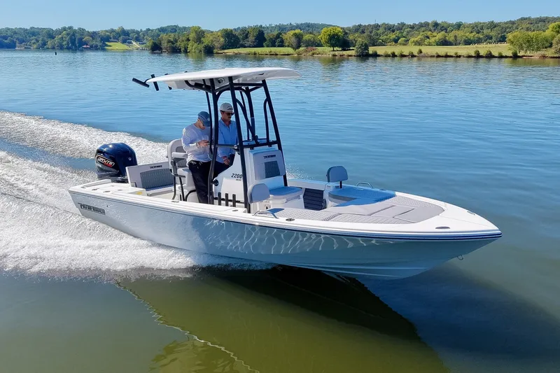 The Image of A modern Pathfinder 2200 Hybrid glides over calm water. Two people are steering the boat. - 0