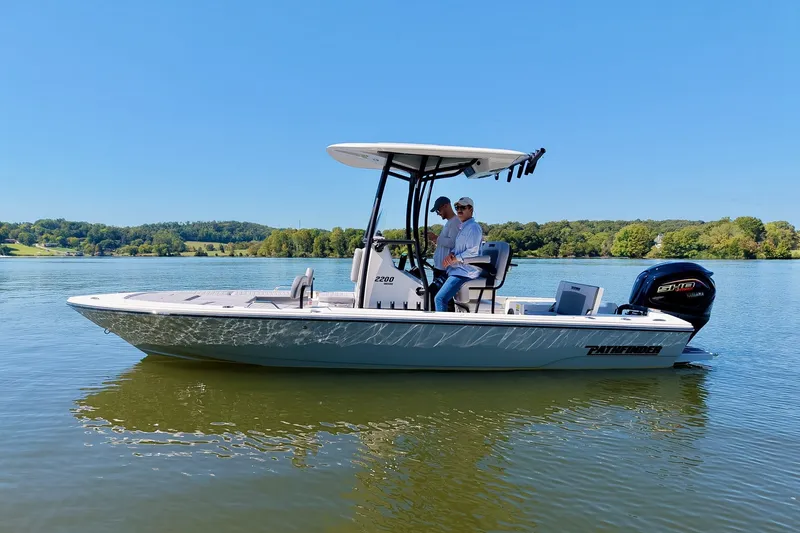 Slide: The Image of 2027 Pathfinder 2200 Hybrid boat on a serene lake with two passengers. - 30