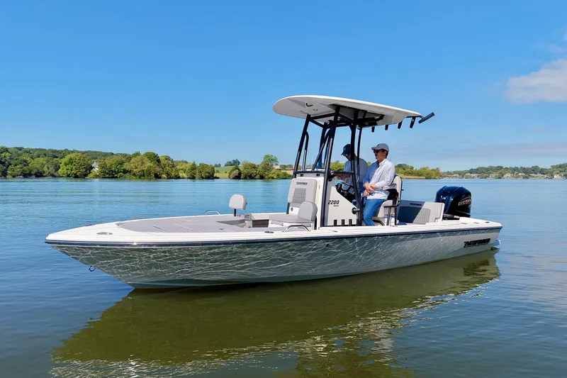 Slide: The Image of 2027 Pathfinder 2200 Hybrid boat cruising on a calm lake under a clear blue sky. - 26