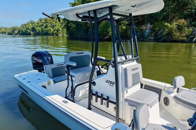 Slide: The Image of 2027 Pathfinder 2200 Hybrid boat on calm lake with lush green shoreline. - 6