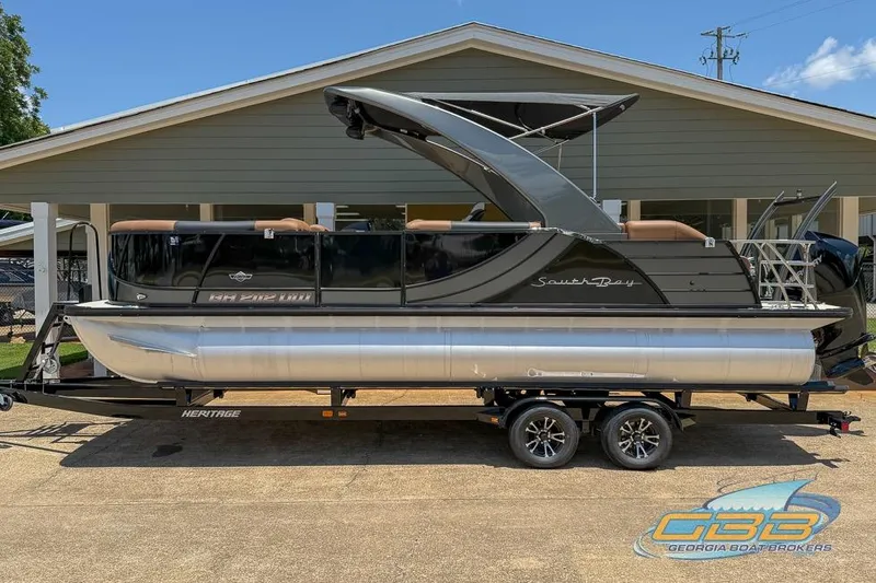 Slide: The Image of 2022 South Bay 523 SB2 ARCH pontoon boat on trailer, parked outside a building. - 3
