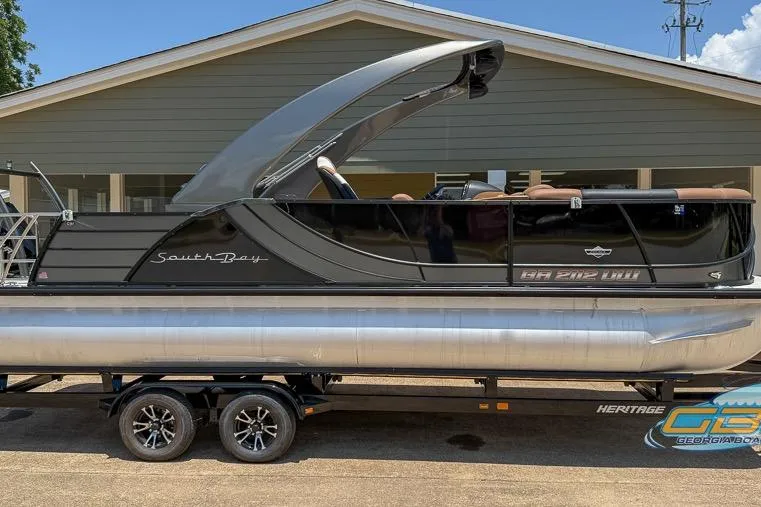 Slide: The Image of 2022 South Bay 523 SB2 ARCH pontoon boat on trailer, parked outside a building. - 12