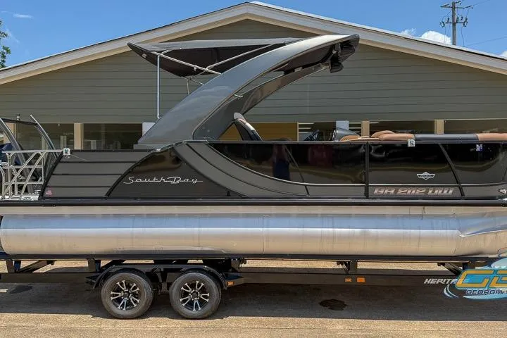 Slide: The Image of 2022 South Bay 523 SB2 ARCH pontoon boat on trailer, parked in front of a house. - 10