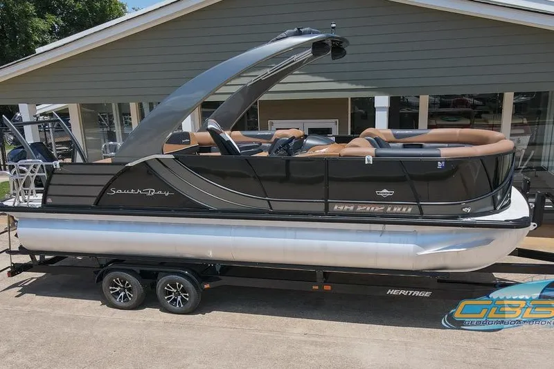 Slide: The Image of 2022 South Bay 523 SB2 ARCH pontoon boat on trailer, parked outside a building. - 25
