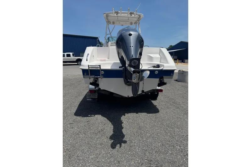 Slide: The Image of 2006 Pro-Line 24 Walkaround boat with outboard motor, parked on asphalt. - 7
