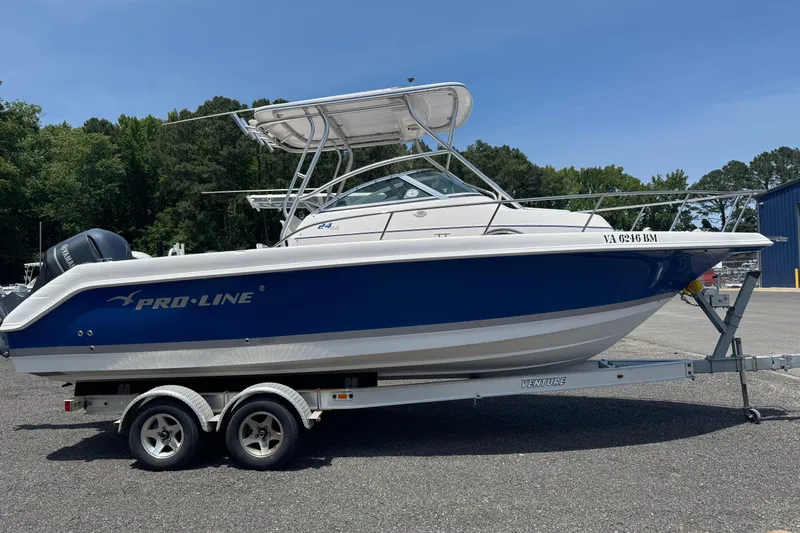 The Image of 2006 Pro-Line 24 Walkaround boat on trailer, parked outdoors under clear sky. - 1