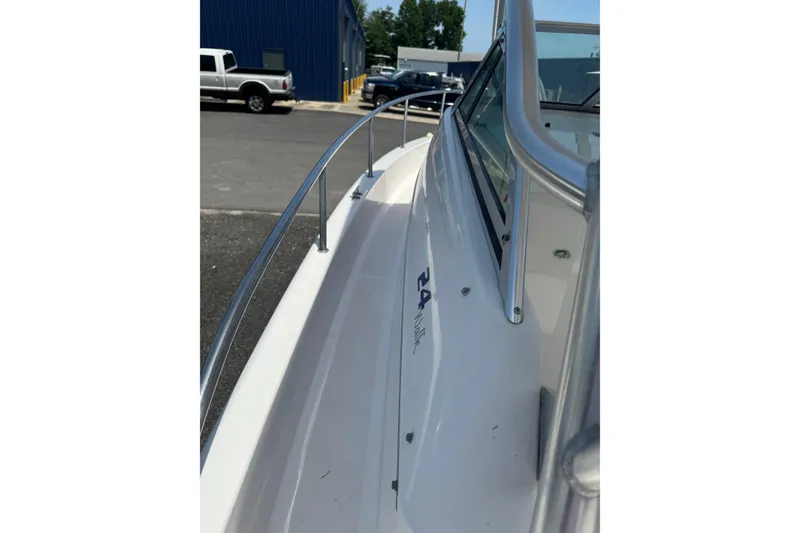 Slide: The Image of 2006 Pro-Line 24 Walkaround boat, side view with railing, parked near a blue building. - 18