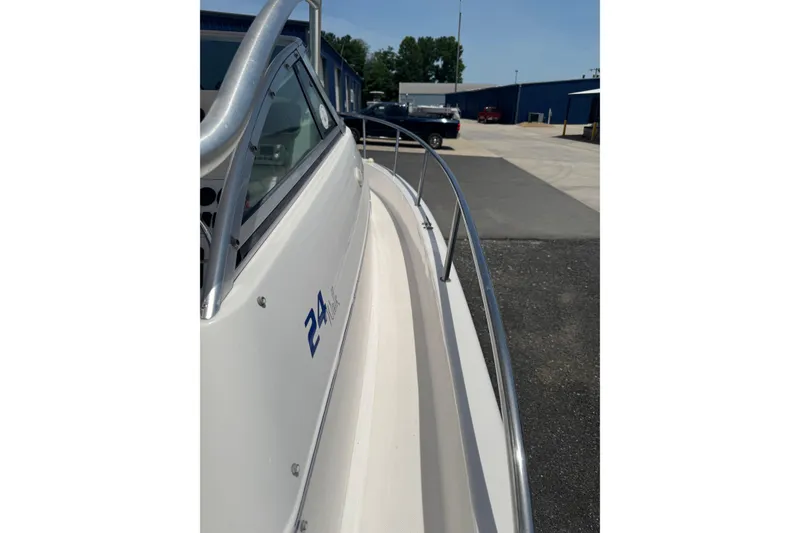 Slide: The Image of 2006 Pro-Line 24 Walkaround boat, side view with railing, parked outdoors. - 19