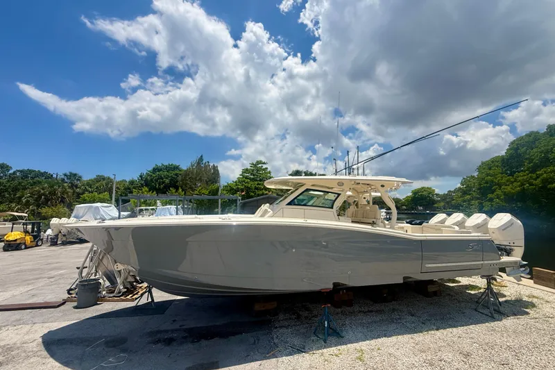 The Image of 2026 Scout 400 LXF boat on dry dock under a partly cloudy sky. - 0