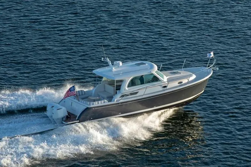 The Image of 2027 Back Cove 34O cruising on open water, displaying sleek design and American flag. - 0