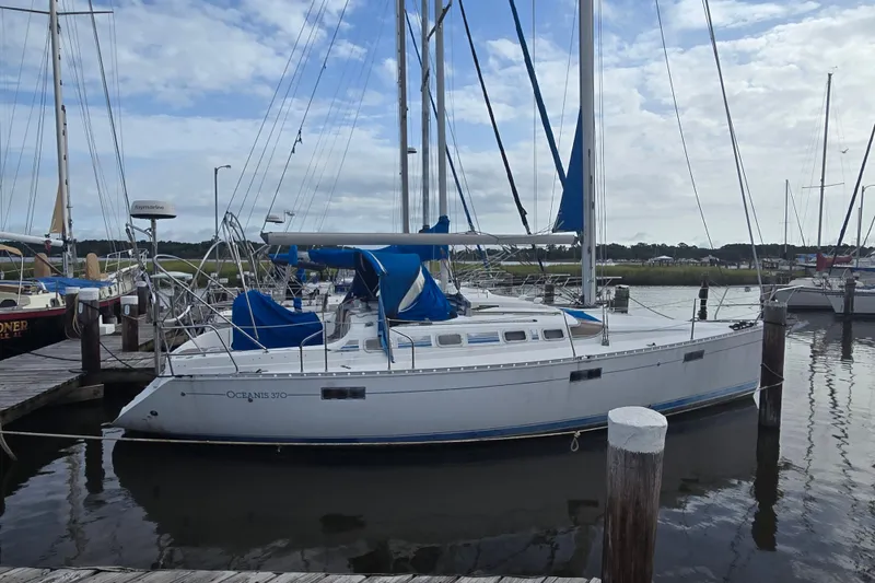 The Image of 1993 Beneteau Oceanis 370 sailboat docked at a marina under a cloudy sky. - 0