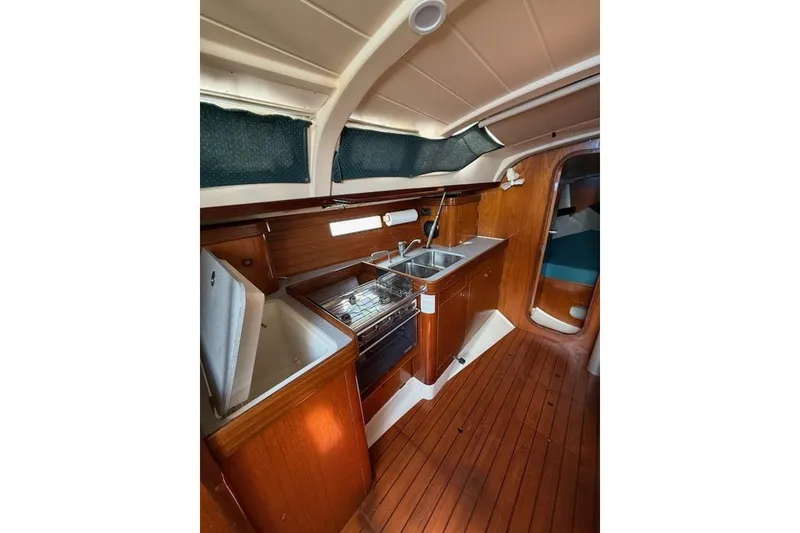 Slide: The Image of Interior of 1993 Beneteau Oceanis 370 yacht, featuring a compact kitchen with wood finish. - 11