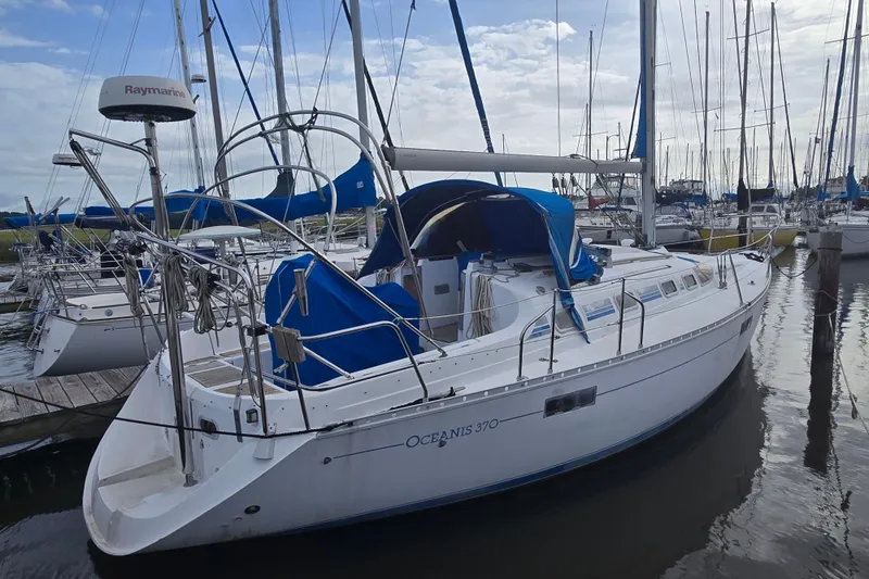 Slide: The Image of 1993 Beneteau Oceanis 370 sailboat docked in marina, featuring blue covers and sleek design. - 2