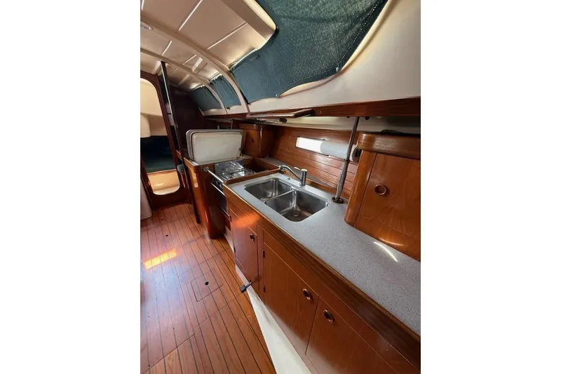Slide: The Image of Interior of 1993 Beneteau Oceanis 370 yacht, featuring a wooden galley with sink and storage. - 12