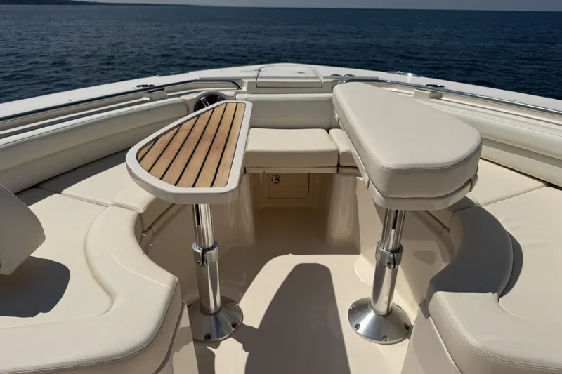 Slide: The Image of 2019 Grady-White Canyon 456 boat interior with cushioned seating and wooden table on open water. - 35